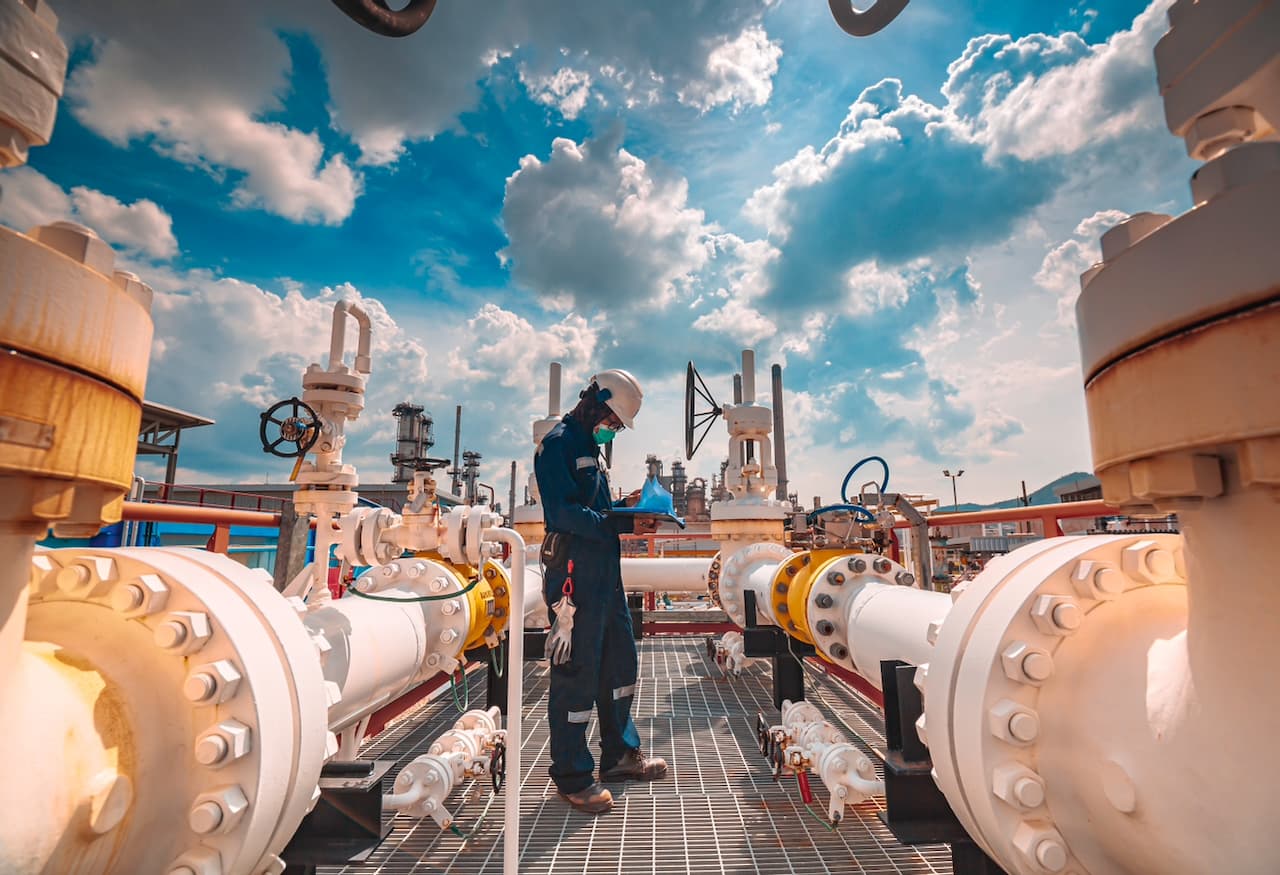 Trabajador industrial revisando válvulas y tuberías en una planta, reflejando los altos estándares de calidad en los productos de MMTubería para la industria energética.