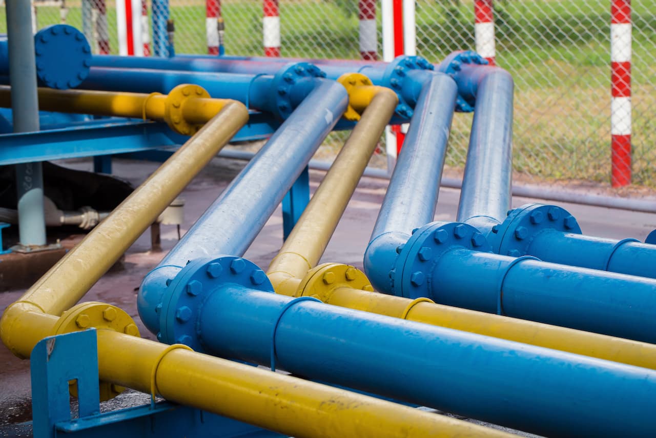 Tuberías de acero pintadas de amarillo y azul en una planta, mostrando la versatilidad y alta calidad de los productos de MMTubería en aplicaciones industriales.