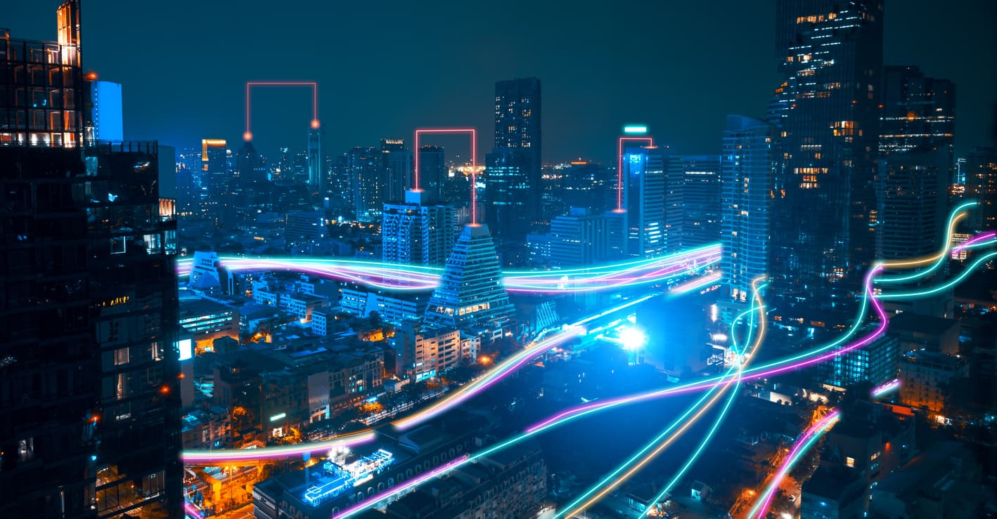 Vista nocturna de una ciudad moderna con edificios iluminados y líneas de luces vibrantes, simbolizando el alcance nacional y la logística avanzada de MMTubería.