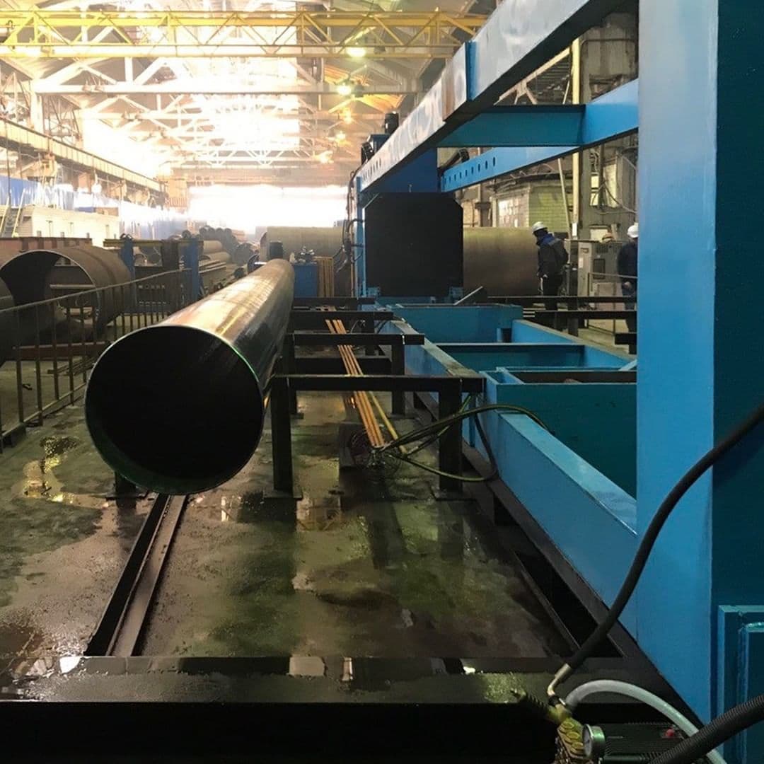 Almacenamiento de tubos de acero en un taller industrial, con un trabajador inspeccionando los materiales.