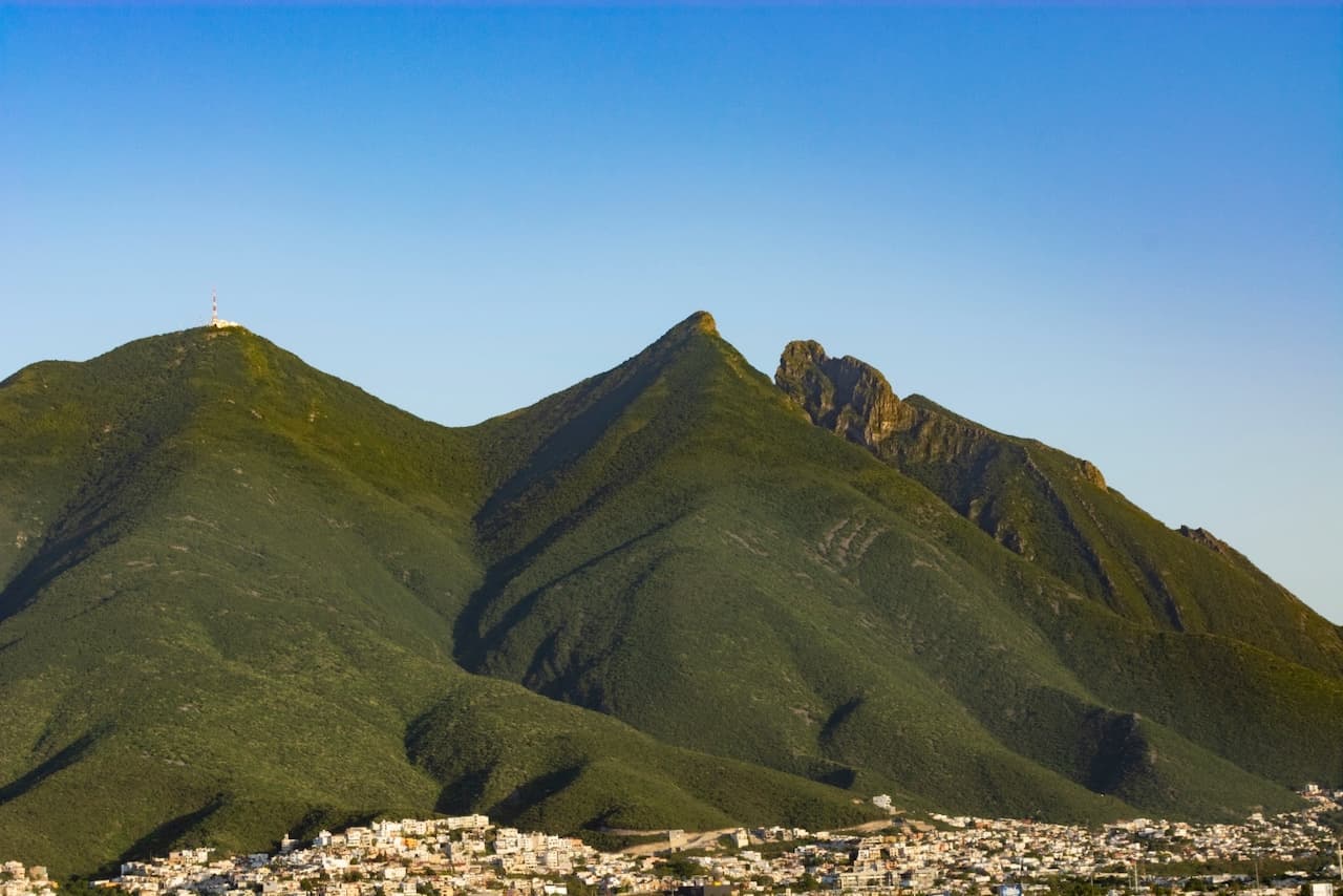 Montaña verde con cielo despejado, representando el alcance de MMTubería en la geografía diversa de México, proporcionando soluciones de tuberías de acero duraderas y de alta calidad.