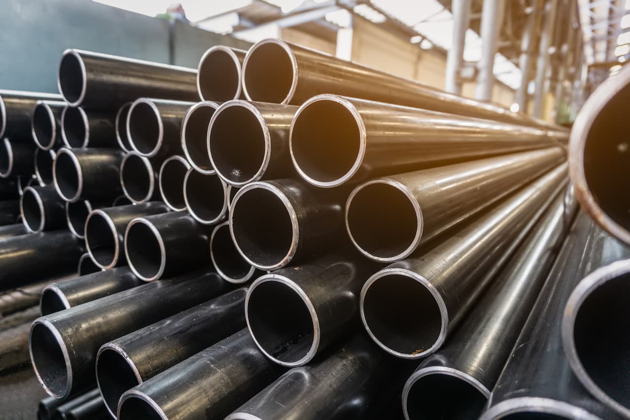Tuberías de acero apiladas en una fábrica, representando la durabilidad y alta calidad del proceso de fabricación de MMTubería, especializado en la distribución de tuberías de acero para diversas aplicaciones industriales.