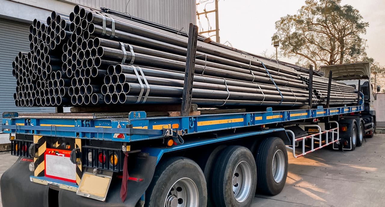 Cargamento de tuberías de acero en un tráiler, mostrando la logística eficiente de MMTubería para la distribución de productos de alta calidad en todo México.