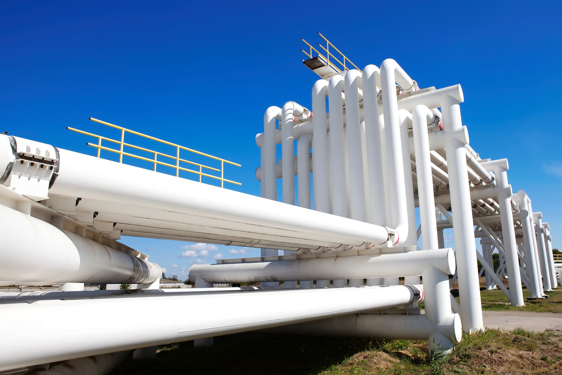 Red de tuberías blancas en una instalación de tratamiento, organizadas meticulosamente sobre estructuras de soporte, destacando la eficiencia y la seguridad en el manejo de sustancias.