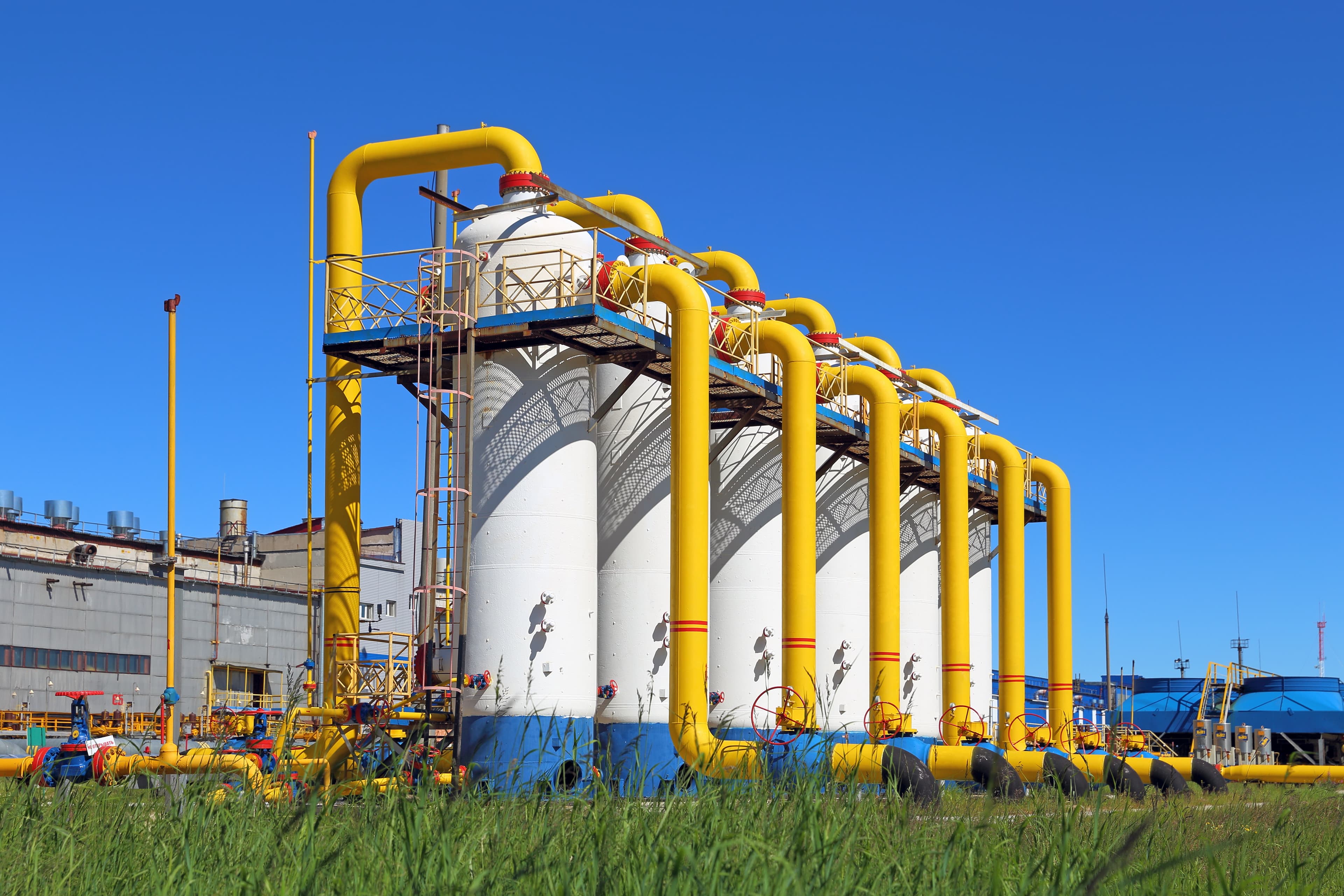 Tanques industriales conectados por tuberías amarillas, mostrando la eficiencia y resistencia de las soluciones de MMTubería en la industria de almacenamiento y transporte de materiales.